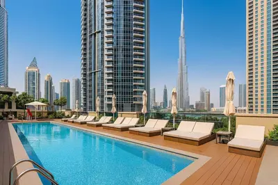 a swimming pool with lounge chairs and a city skyline at Burj Khalifa Area- 2 Chic BR, Act Tower Dubai Mall in Dubai
