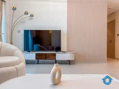 a living room with a tv and a vase on a table at Wake up To Burj Khalifa Views Luxury 2 BR LikeHome in Dubai