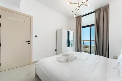 a white bedroom with a white bed and a large window at Modern 1BR with Pool & Gym, Burj Khalifa View, Al Jaddaf in Dubai