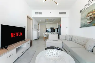 a living room with a couch and a tv at Modern 1BR with Pool & Gym, Burj Khalifa View, Al Jaddaf in Dubai