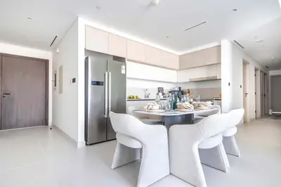 a kitchen with white cabinets and a table and chairs at Frank Porter - Marina Vista Tower 2 in Dubai