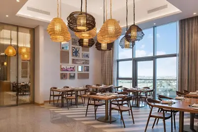 a restaurant with tables and chairs and large windows at 2BR Apartment in Paramount Midtown with Infinity Pool in Dubai