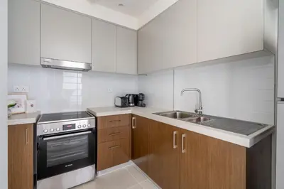 a kitchen with white cabinets and a stove and a sink at GuestReady - Forte Tower | Steps from Dubai Mall in Dubai