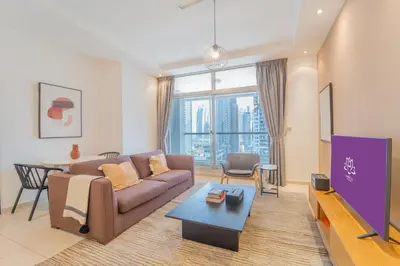 a living room with a couch and a tv at SkyView Tower - Dubai Marina View - Lit Apartment in Dubai