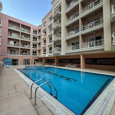 a swimming pool in front of a large apartment building at Stylish Studio Apartment in JVC in Dubai