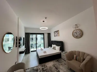 a living room with a bed and a clock on the wall at Captivating Studio in Jvc Elysee in Dubai