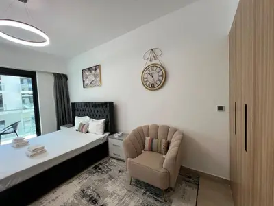 a bedroom with a bed and a chair and a clock at Captivating Studio in Jvc Elysee in Dubai