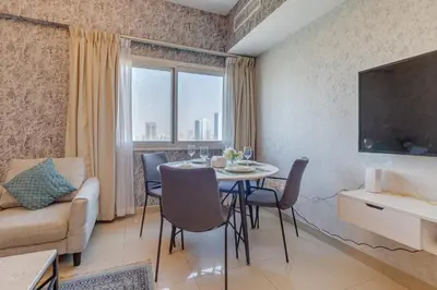 a living room with a table and chairs and a tv at Red Residence, Sports City - 2 Bedroom Apartment - Allsopp & Allsopp in Dubai