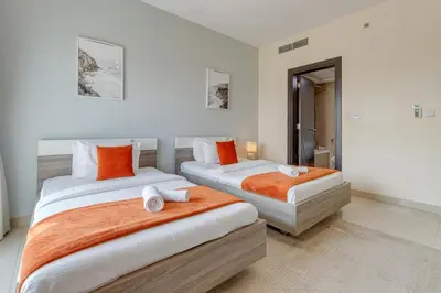two beds in a room with white walls and orange pillows at Red Residence, Sports City - 2 Bedroom Apartment - Allsopp & Allsopp in Dubai