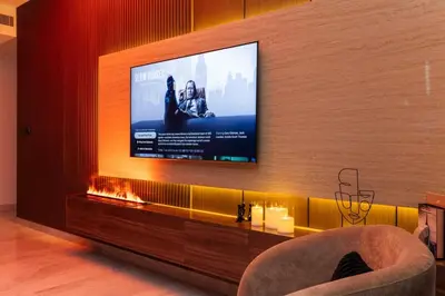 a living room with a television on a wall at 3BR Ultra Luxury Waterfront Panoramic Views with Pool, Gym, Jacuzzi -10 mins to Burj Khalifa in Dubai