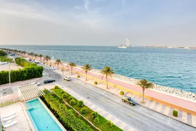 a road next to the water with palm trees at Luxury Apartment at Muraba Residence in Dubai