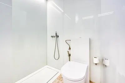 a white bathroom with a toilet and a shower at Luxury Apartment at Muraba Residence in Dubai