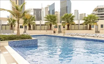 a swimming pool with palm trees and buildings at Bay Central Marina Suite with Exceptional Views in Dubai