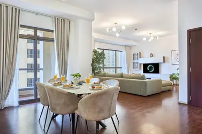 a dining room and living room with a table and chairs at Family Stay JBR 3BR and maids room l Walk to Beach l Marina in Dubai