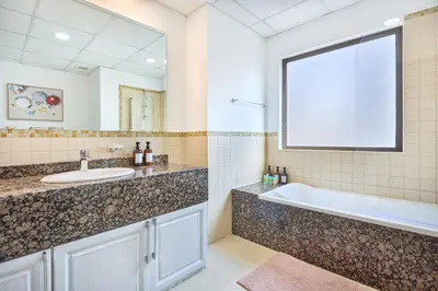 a bathroom with a tub and a sink and a mirror at Family Stay JBR 3BR and maids room l Walk to Beach l Marina in Dubai