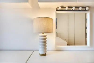 a lamp on a table in a room with a mirror at Family Stay JBR 3BR and maids room l Walk to Beach l Marina in Dubai