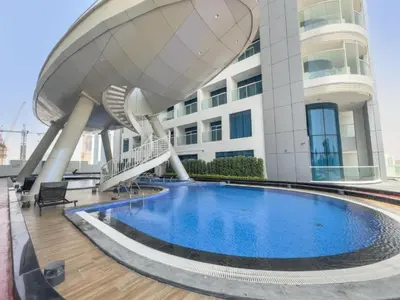 a building with a swimming pool in front of a building at Vacationer l Elegant 1 Bedroom l Arjan l Pool with View Deck in Dubai