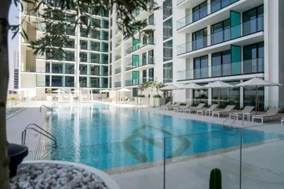 a large swimming pool with chairs and a building at Vacationer l Classy 2 Bedroom l Private Jacuzzi l near Circle Mall in Dubai