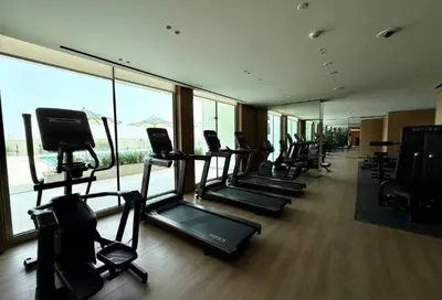 a gym with rows of treadmills and a large window at Vacationer l Classy 2 Bedroom l Private Jacuzzi l near Circle Mall in Dubai
