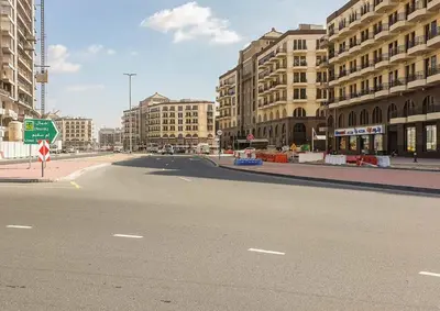 an empty street in a city with tall buildings at Vacationer I Modern Studio I Pool & Gym Access I 5-min Drive to Miracle Garden I Arjan in Dubai
