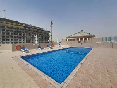 a large swimming pool with chairs and a building at Vacationer I Modern Studio I Pool & Gym Access I 5-min Drive to Miracle Garden I Arjan in Dubai