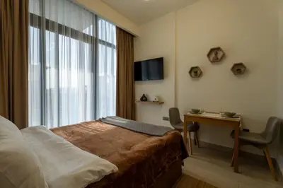 a hotel room with a bed and a desk and a window at Roomook Cozy studio in Dubai