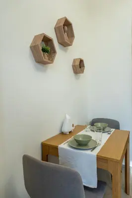 a dining room table with two chairs and a wooden table with plates at Roomook Cozy studio in Dubai
