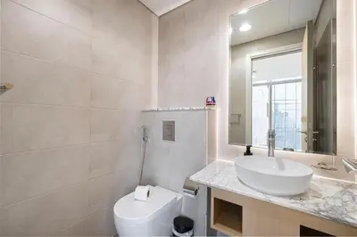a bathroom with a sink and a toilet and a mirror at Highest Infinity Pool - Paramount Midtown Hotel & Luxury Apartments Burj Khalifa view & Partial Fountain View in Dubai
