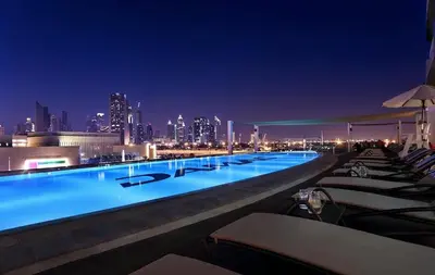 a swimming pool with a city skyline at night at Damac Maison Downtown Dubai Luxury 1BR Walk to Dubai Mall in Dubai