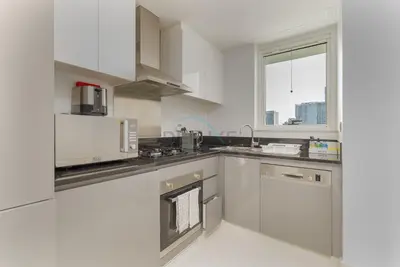 a kitchen with stainless steel appliances and a window at Picture-Perfect Canal and City Views, Minutes from Waterfront Transport, Easy Access to Downtown Delights, Prive by Damac B, Business Bay by Deluxe Holiday Homes in Dubai