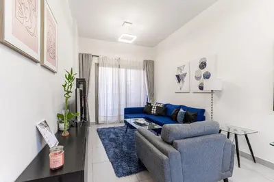 a living room with a blue couch and a chair at HAVN - 1 bedroom in The Wings, Arjan in Dubai