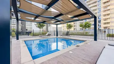 a swimming pool with awning over a building at HAVN - Cozy 1 bedroom in Golfville in Dubai