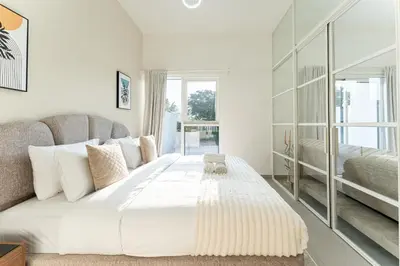 a white bedroom with a large bed and a couch at HAVN - Cozy 1 bedroom in Golfville in Dubai