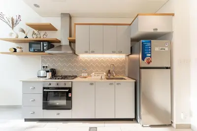 a kitchen with white cabinets and a refrigerator at HAVN - Cozy 1 bedroom in Golfville in Dubai