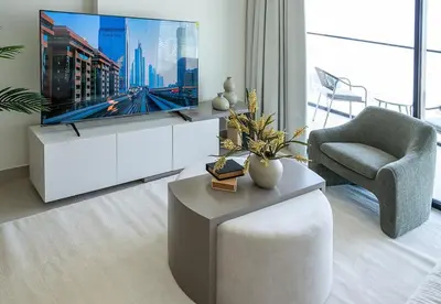a living room with a tv and a couch and a chair at Modern 1 Bed Apartment in Binghatti Orchid in Dubai