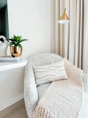 a white chair sitting next to a table with a lamp at Radiant Studio in Binghatti Azure with Pool & Gym in Dubai