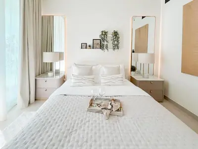 a white bedroom with a white bed with a mirror at Radiant Studio in Binghatti Azure with Pool & Gym in Dubai