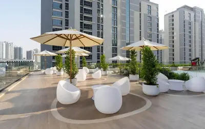 a row of white chairs and umbrellas on a rooftop at Airy 1BR Oasis with Plunge Pool in Binghatti Phantom in Dubai