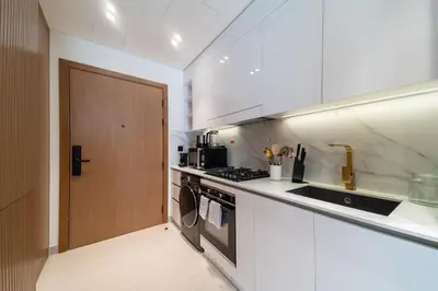 a kitchen with a stove and a sink and a door at Beautifully Furnished Studio in Binghatti Azure in Dubai