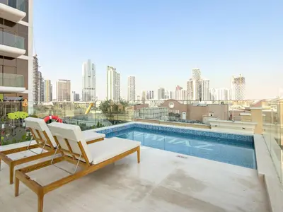 a balcony with a chair and a swimming pool at VayK - Modern & Elegant 1BD in JVC in Dubai
