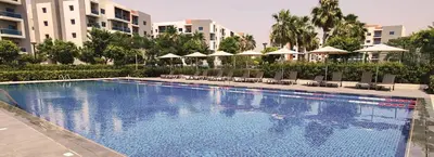 a large swimming pool with chairs and umbrellas at Furnished 2 Bedroom Apartment with Balconies in Dubai