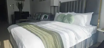 a large white bed with a green blanket on it at Studio in JLT near Metro - Close to Marina, JBR in Dubai