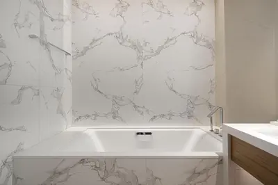 a white bath tub in a bathroom with marble walls at Address Opera by NAMUVE in Dubai