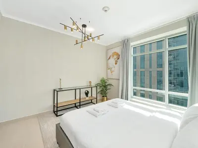 a white bedroom with a large bed and a window at Skyline Upscale 2 Bedroom Apartment I Steps to Burj Khalifa Dubai Fountain Dubai Mall I Mesmerizing Views I Free Gym, Pool, Parking & Wi-Fi in Dubai