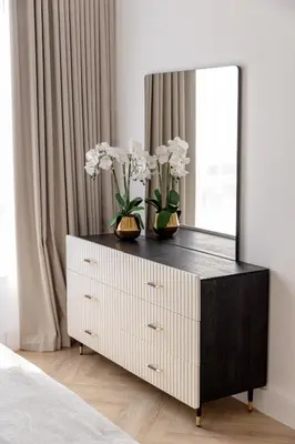 a dresser with a mirror and vases with flowers on it at Beautiful 1 bed in JBR! in Dubai
