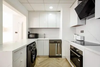 a kitchen with white cabinets and a washer at Beautiful 1 bed in JBR! in Dubai