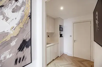 a kitchen with white cabinets and a painting on the wall at Stylish Studio with Marina View JBR in Dubai