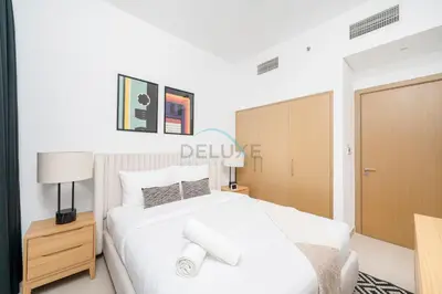 a bedroom with a white bed and a wooden cabinet at Harbour-View 3BR with Assistant Room, Just a Stones Throw from Marine Transportation, Harbour Gate Tower 1, Creek Harbour by Deluxe Holiday Homes in Dubai