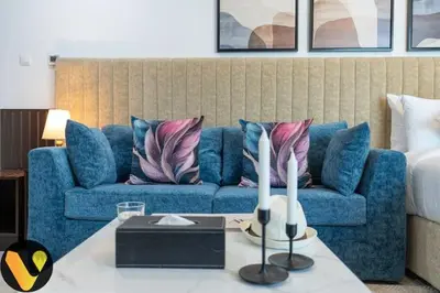 a living room with a blue couch and a table at Vogue Business Bay Court Tower close to Downtown Burj Khalifa and Dubai Mall, Studio Apartment with Canal view in Dubai