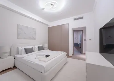 a white bedroom with a white couch and a tv at StayShort - 2 Bedroom in Dubai Marina with Huge Balcony in Dubai